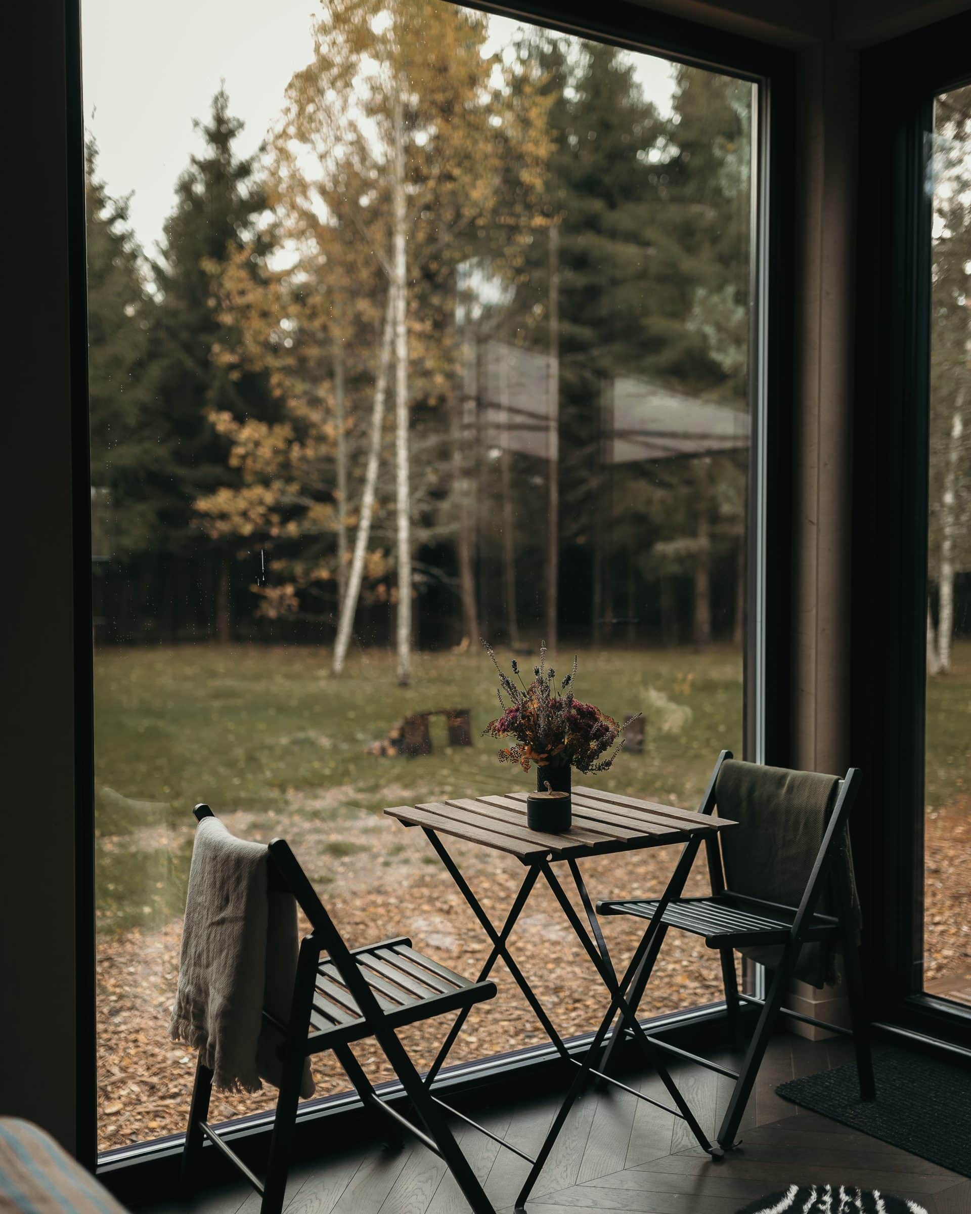 Two folding chairs and a small table facing a full-height window onto the snow forest