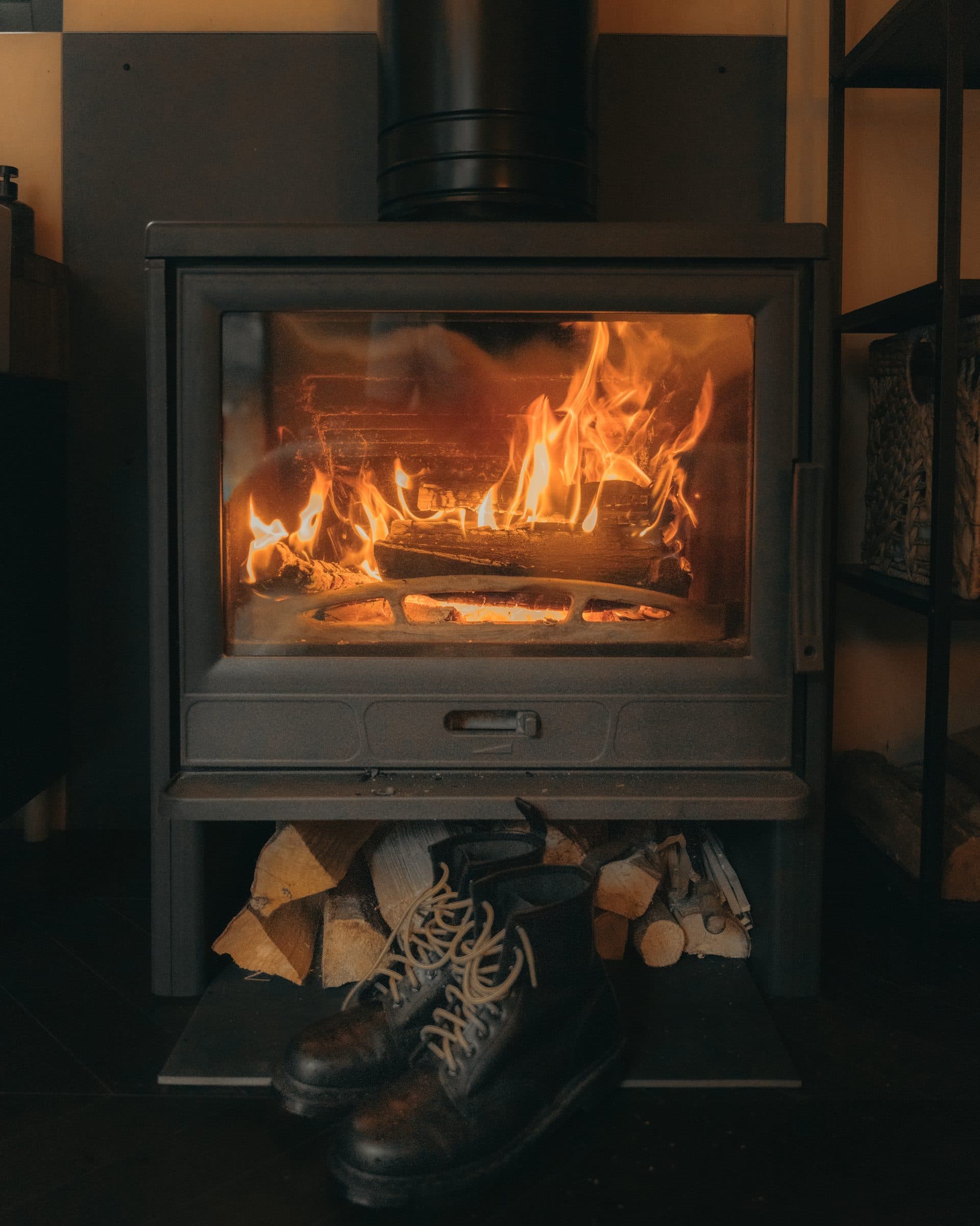 The wood stove — glass front, flames, firewood underneath