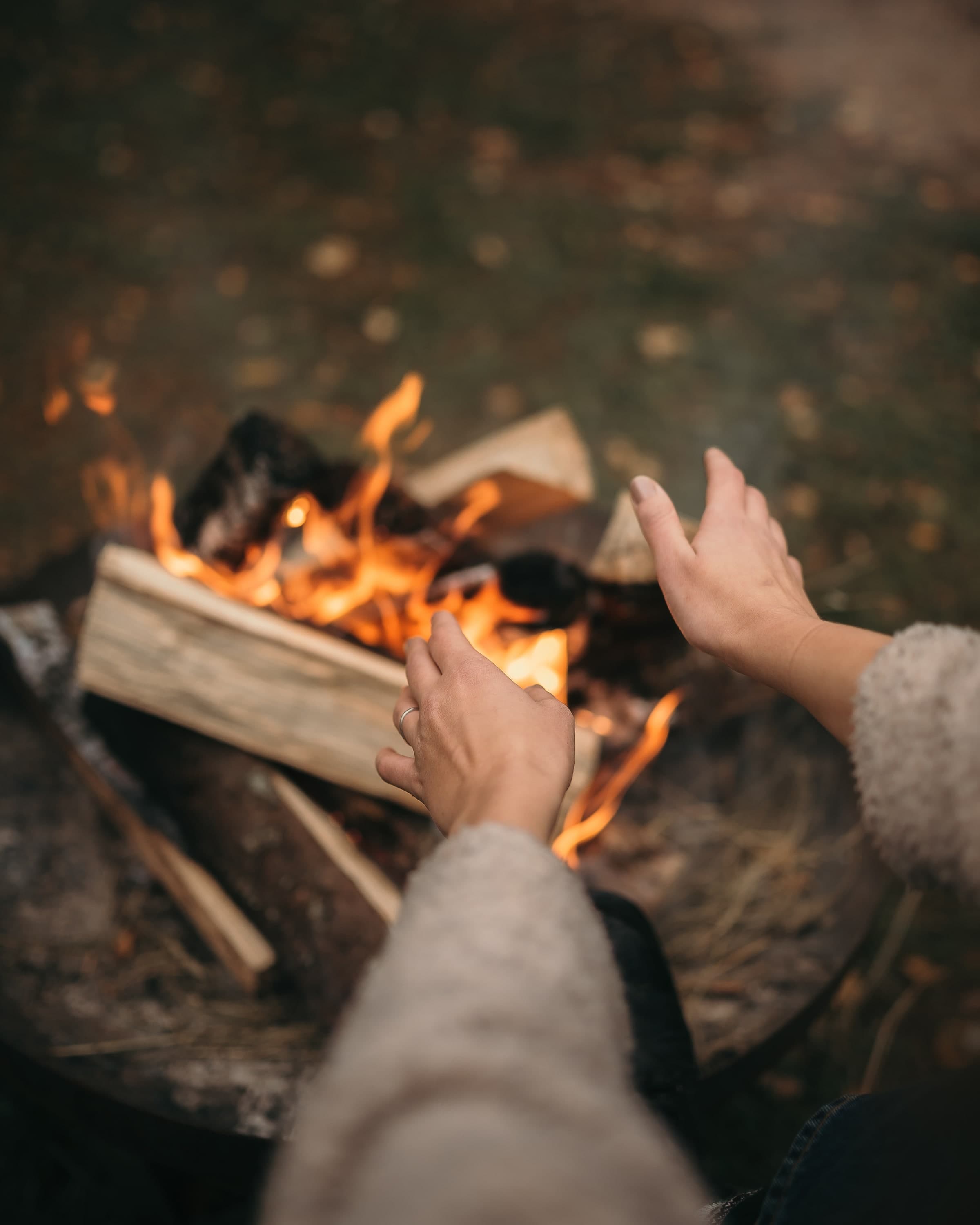 Hands warming over the fire pit, evening